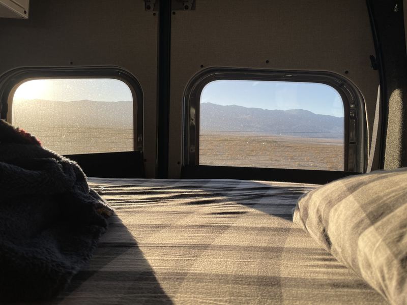View from the bed out the rear windows to a desert landscape at sunrise
