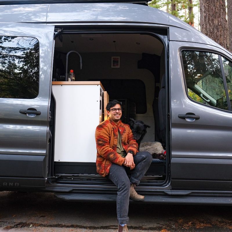 Owner and their dog sitting in the open sliding door of the van