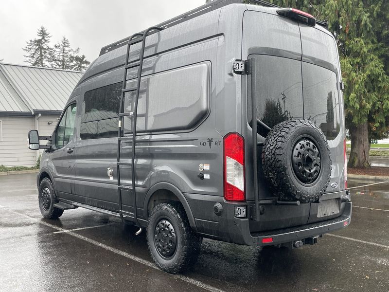 Rear three-quarter view showing the spare tire, ladder and roof rack